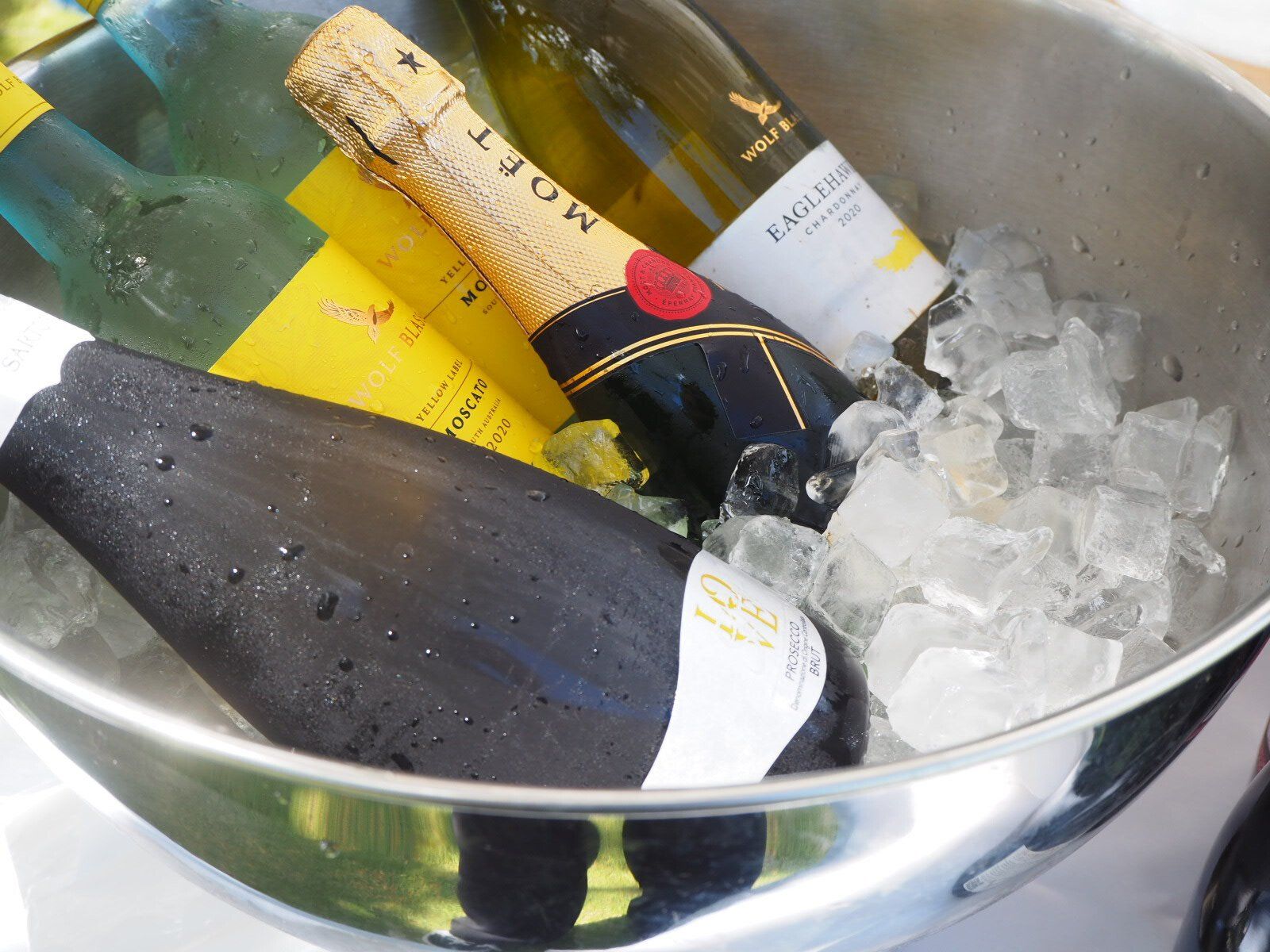 Bottles of wine and champagne chilling in a silver ice bucket.