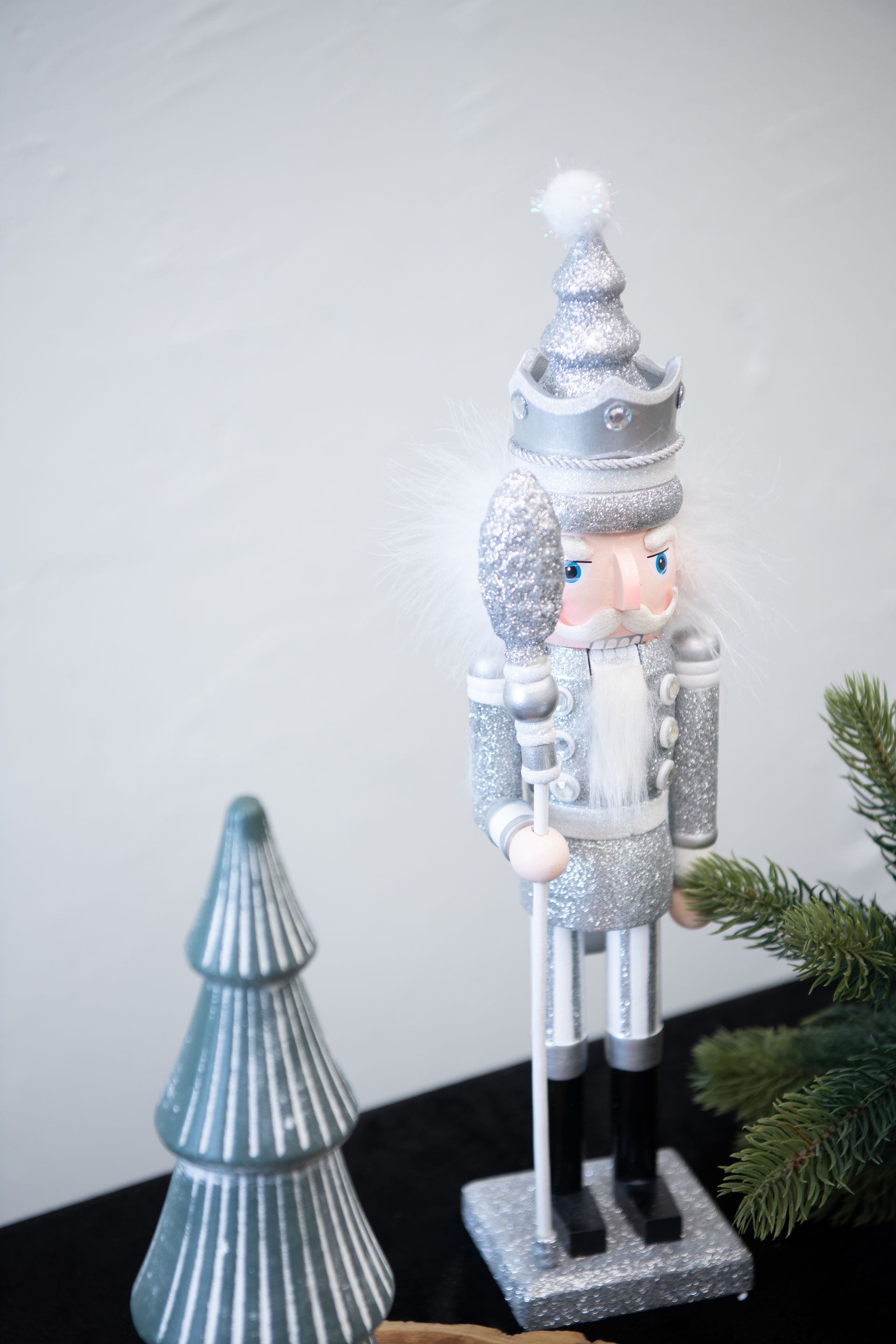Silver nutcracker soldier with a grey tree and greenery.