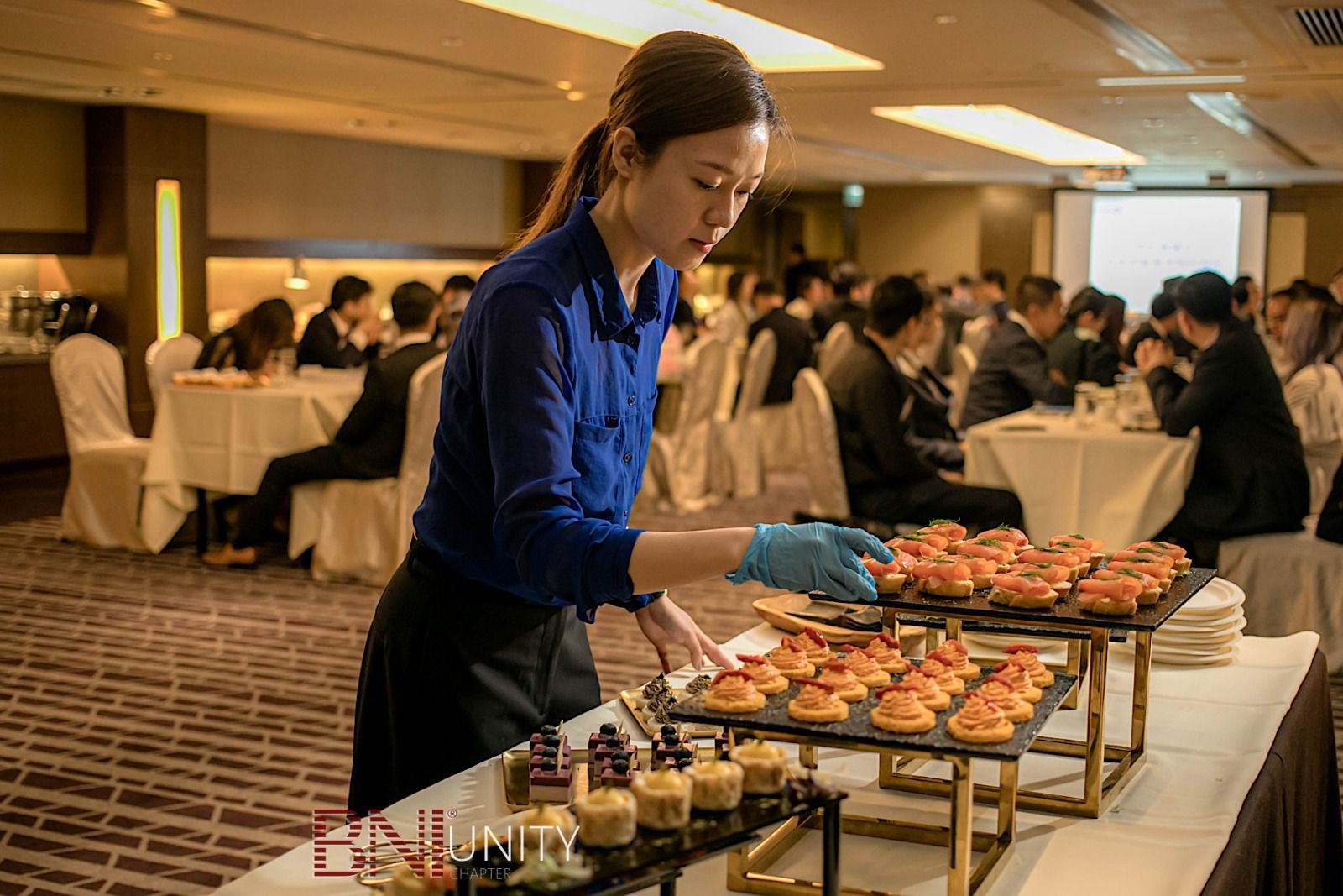 Server arranging appetizers at a catered event.