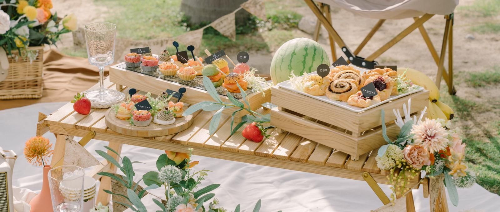 Picnic setup with food, flowers, and a watermelon.