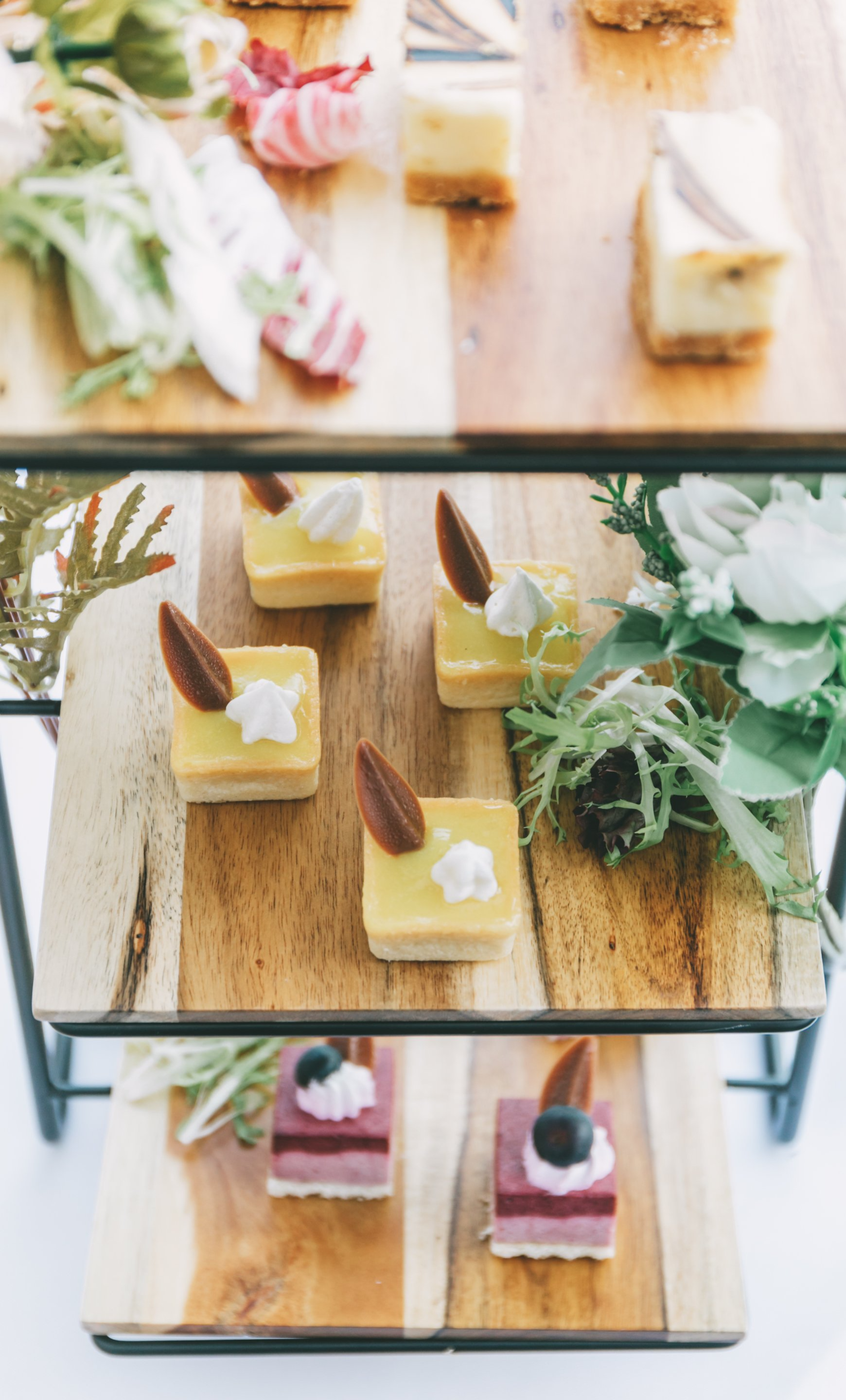 Dessert tiered platter with assorted colorful miniature pastries and garnishes.