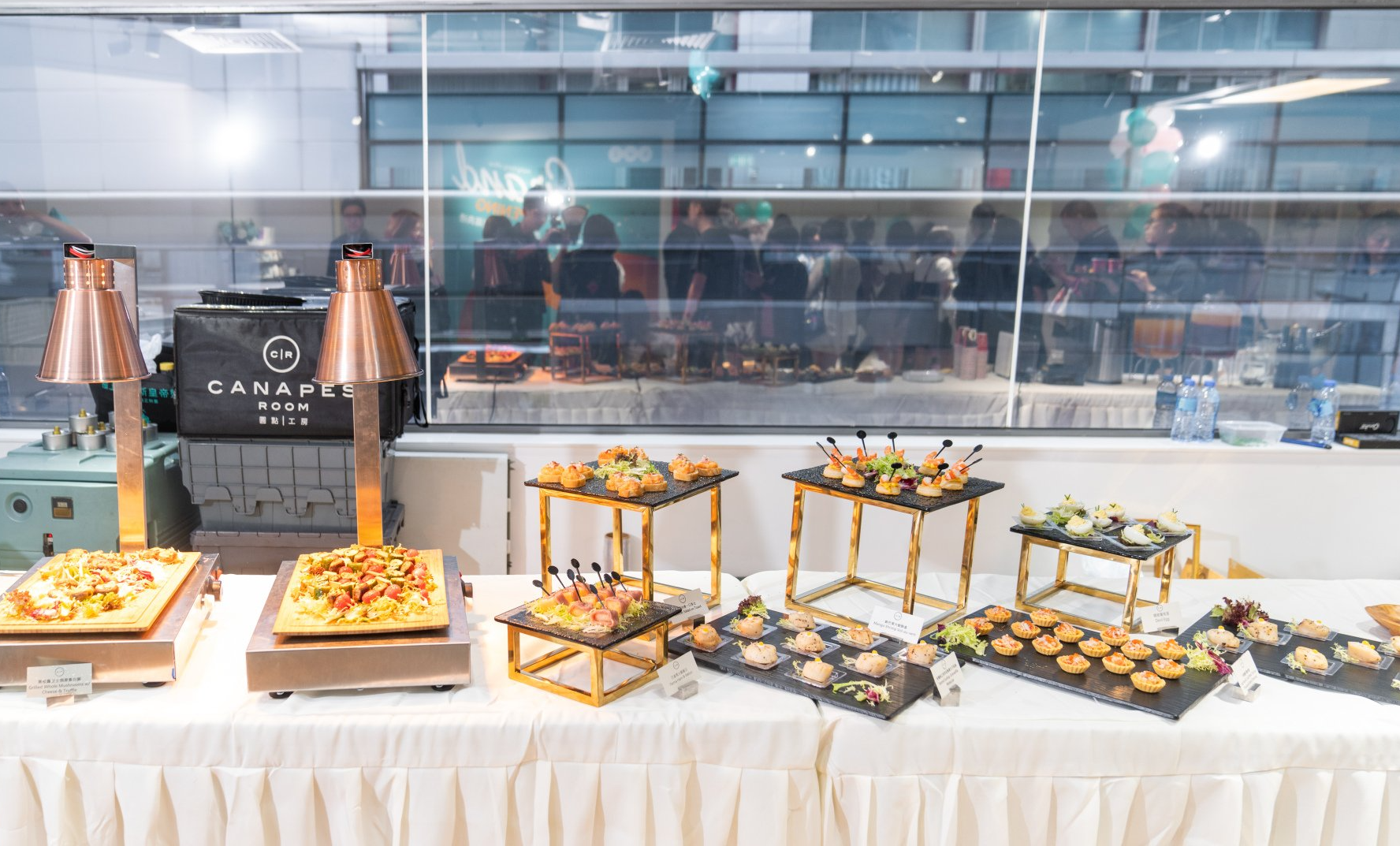 自助餐桌上擺滿了各種開胃菜，旁邊還有加熱燈。派對場景，背景模糊。