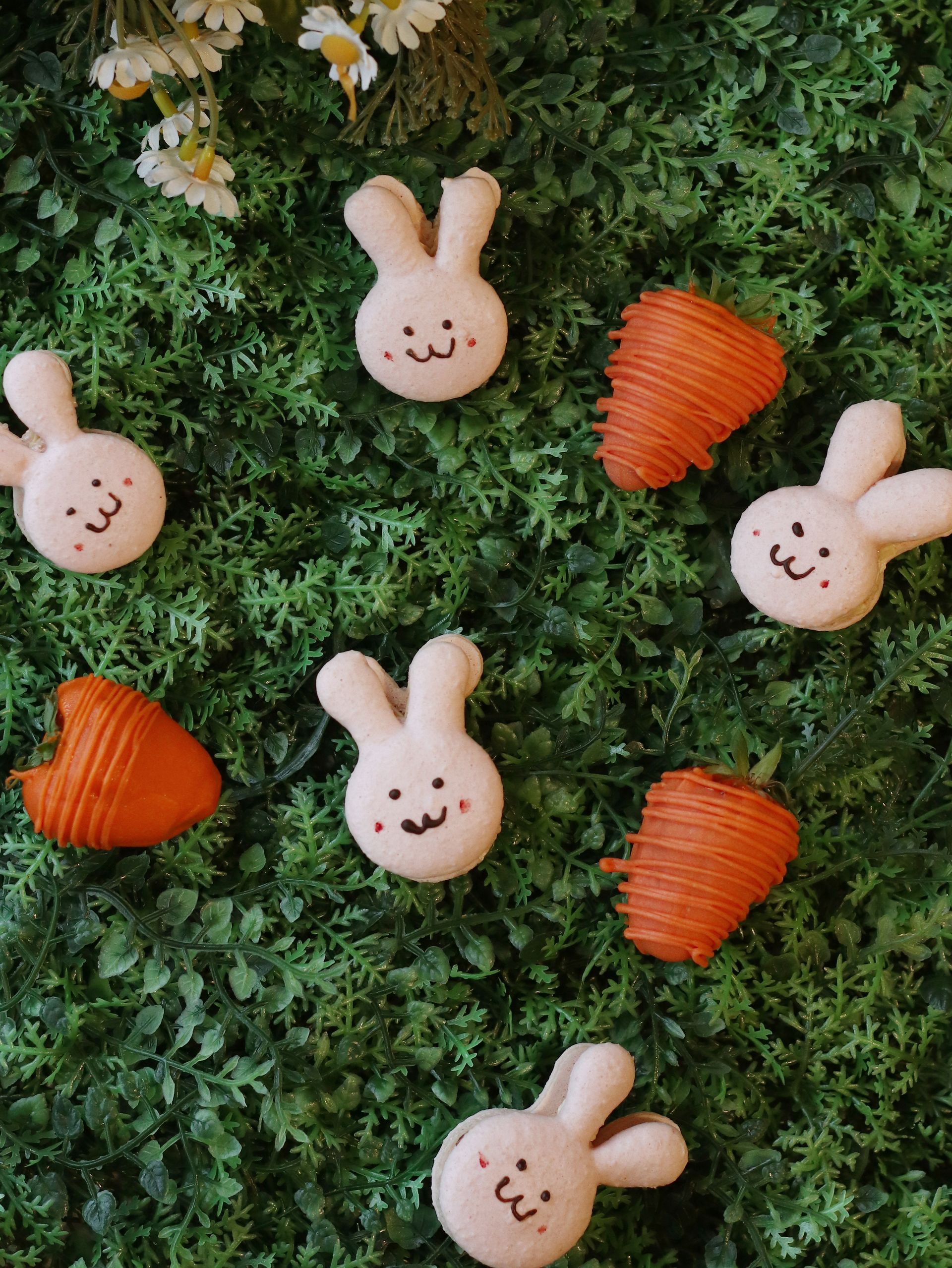 Bunny and carrot macarons on a bed of green faux grass.