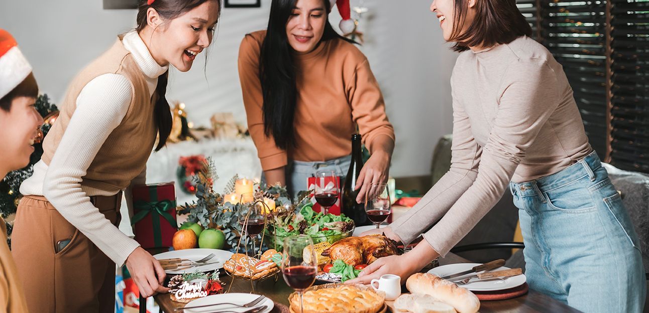 People gather around a table set for a holiday meal, preparing and enjoying the food together.