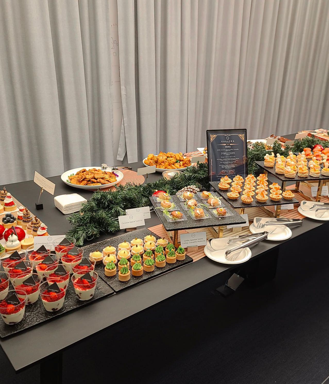 Buffet table with various appetizers and desserts, including pastries and small sandwiches.