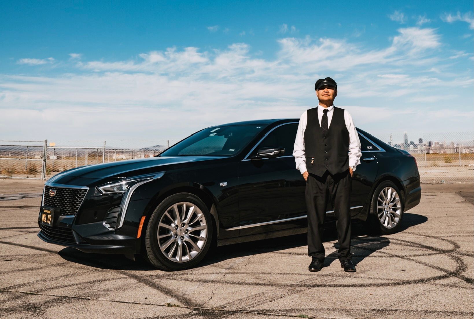 A man in a suit and tie is standing next to a black car.