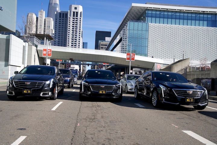 Three black cars are parked on the side of a city street.