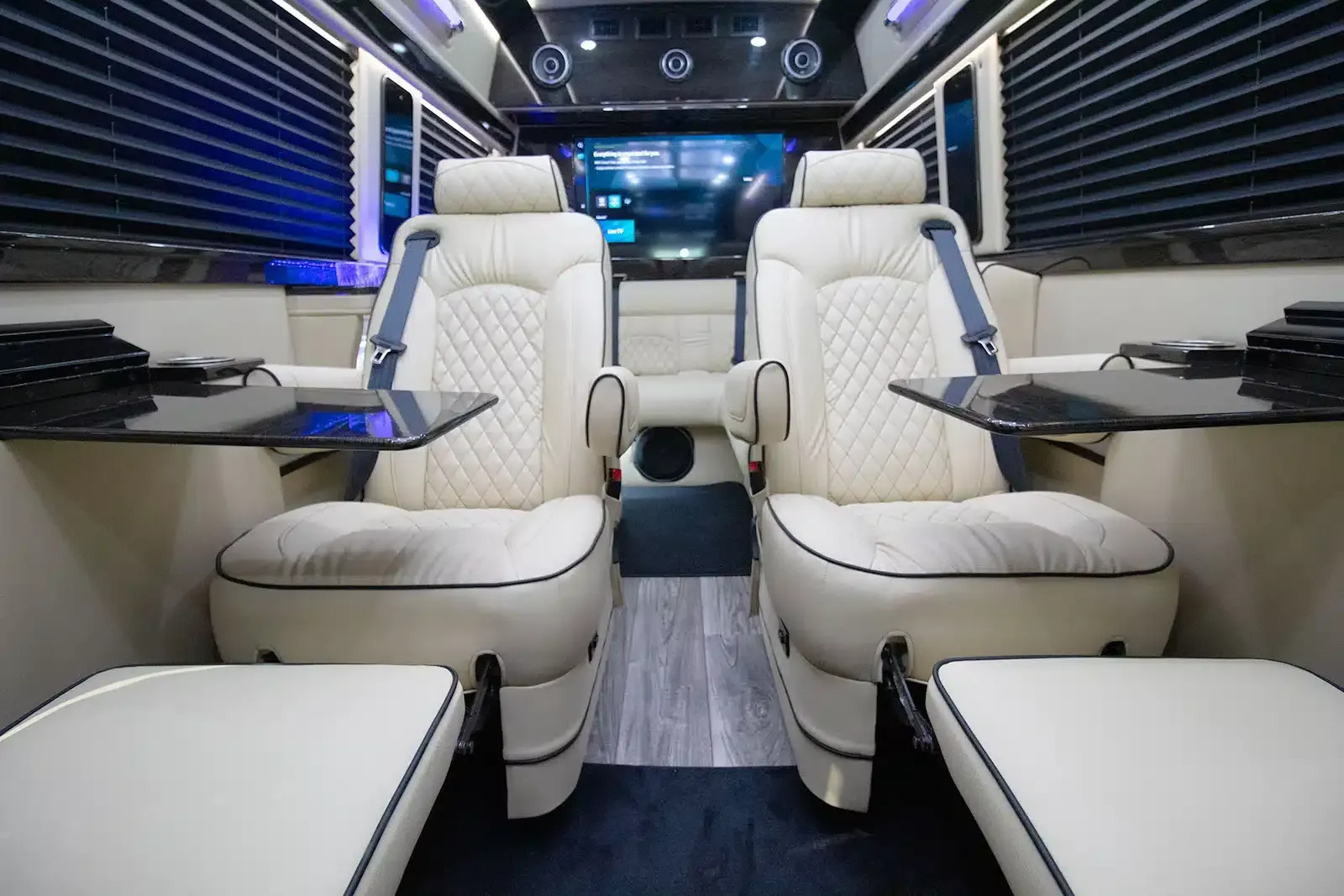 The inside of a van with two white seats and a table.