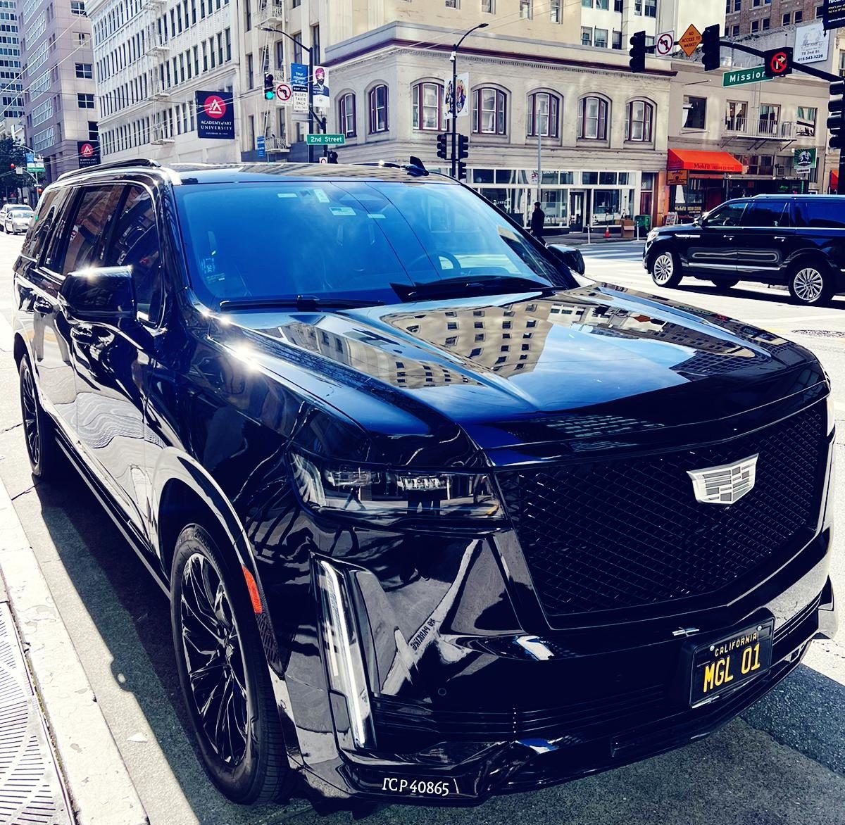 A black cadillac is parked on the side of the road