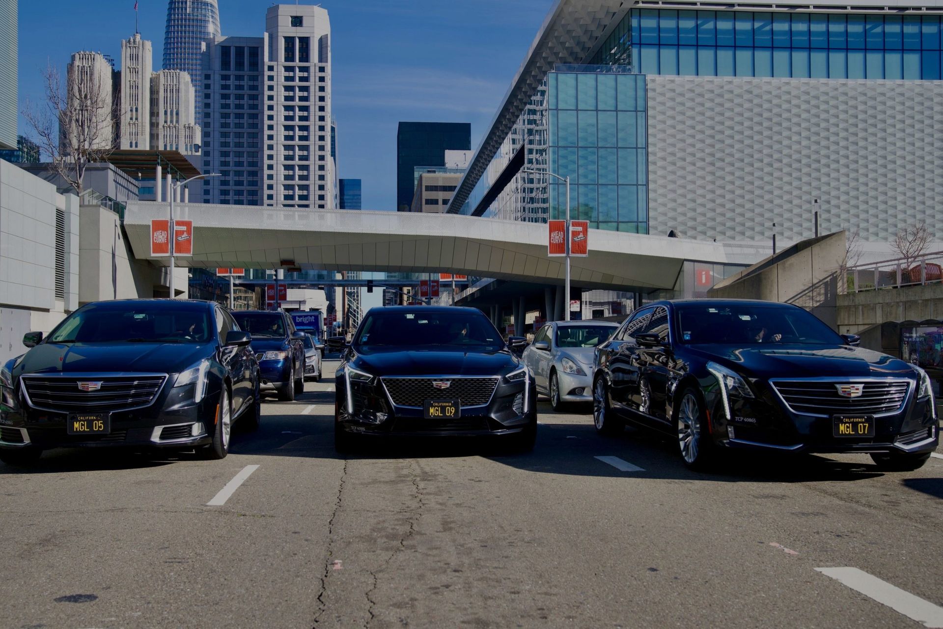 A row of black cars are parked on the side of a city street.