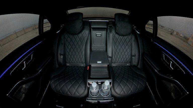 Luxurious black car interior with quilted leather seats, center console, and ambient lighting.