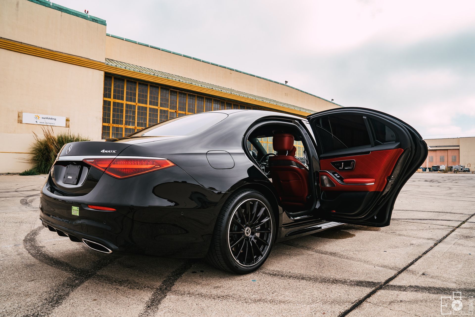 Black Mercedes-Benz sedan with a red interior, parked on a paved lot with the door open.