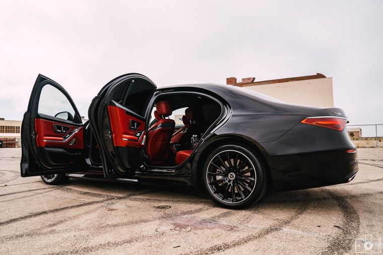 A black car with its doors open is parked in a parking lot.