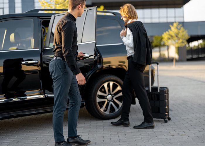 A man is helping a woman get out of a car.