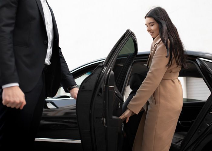 A woman is getting out of a car with a man in a suit.