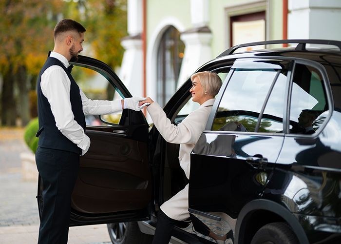 A man is helping a woman get out of a car.
