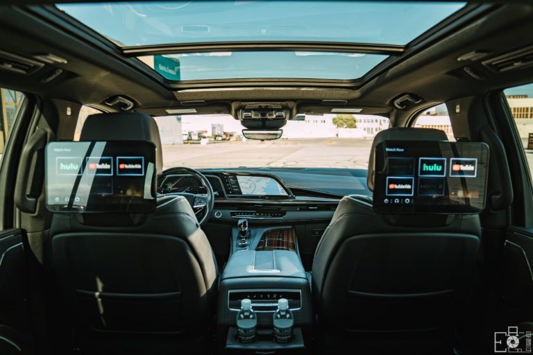 Interior of a luxury SUV, showcasing rear entertainment screens and panoramic sunroof.
