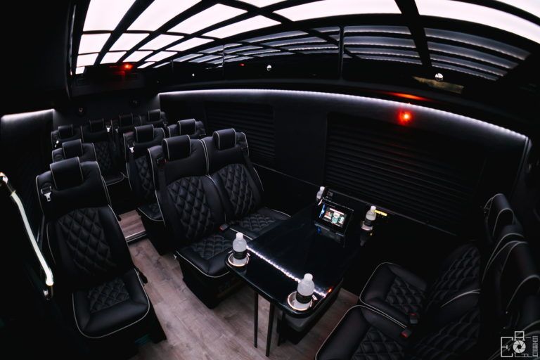 The inside of a bus with black seats and a table