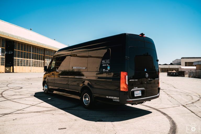A black van is parked in a parking lot in front of a building.