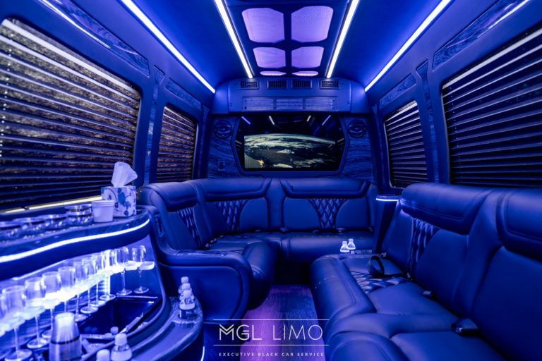 The inside of a limousine with a couch and a bar.