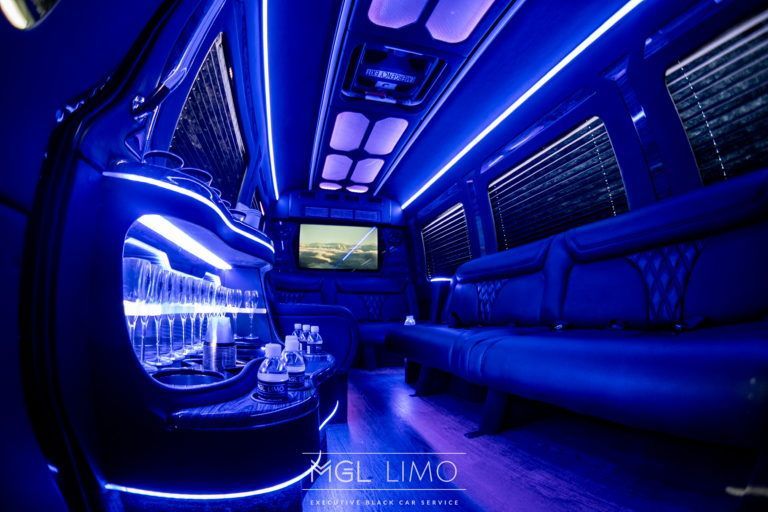 Interior of a limousine with blue LED lighting and a bar area.