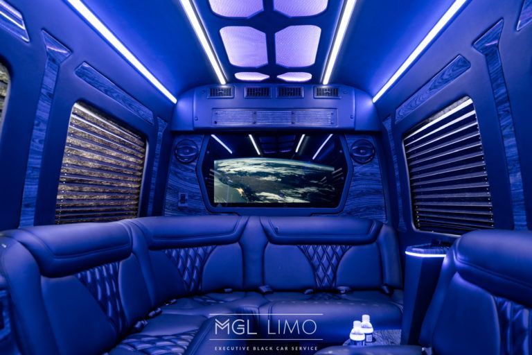 The inside of a limousine with a couch and a television.