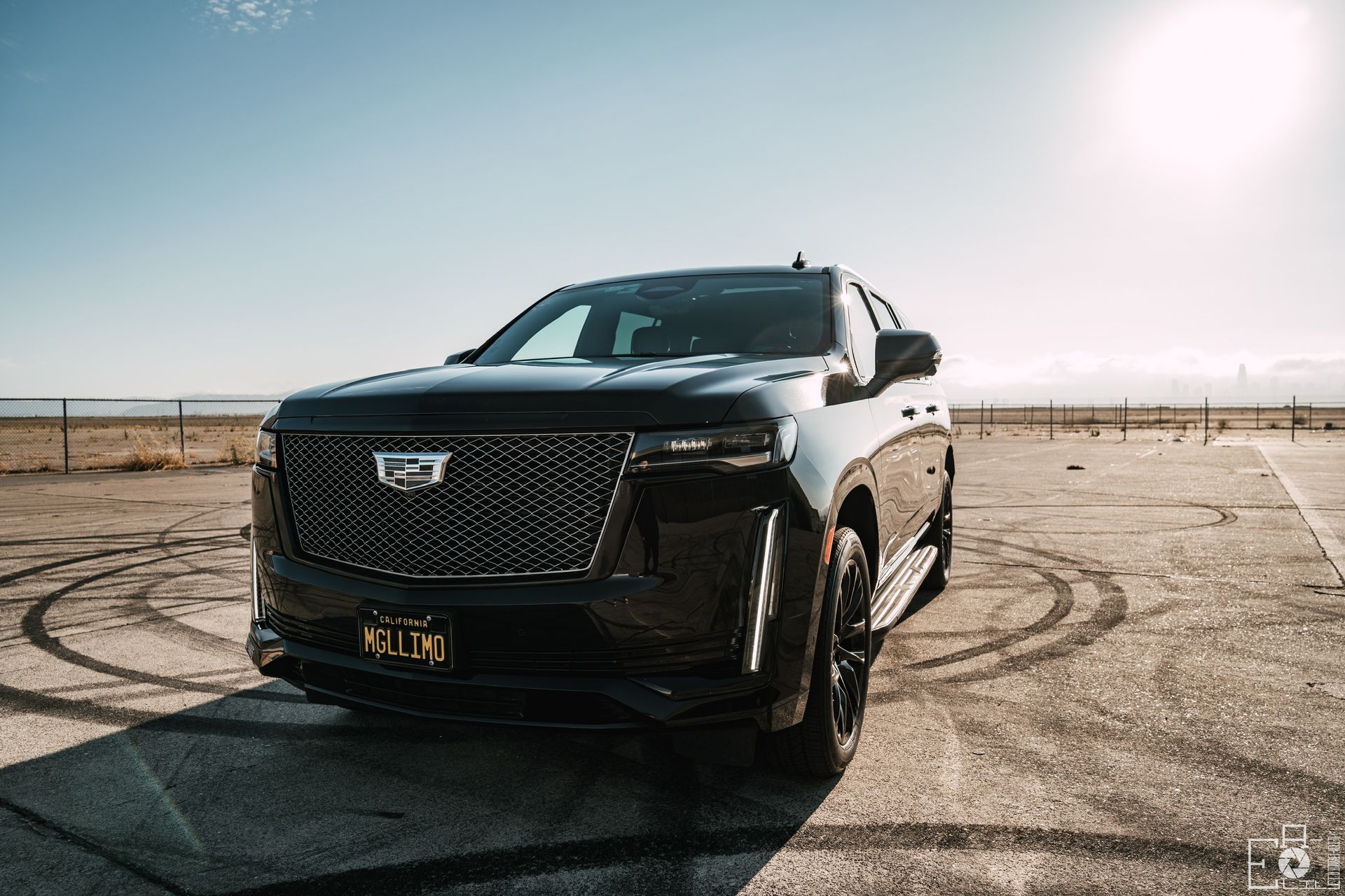 A black cadillac escalade is parked on a dirt road.