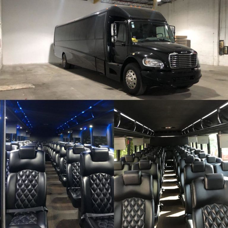 A black bus is parked in a warehouse next to a row of black seats