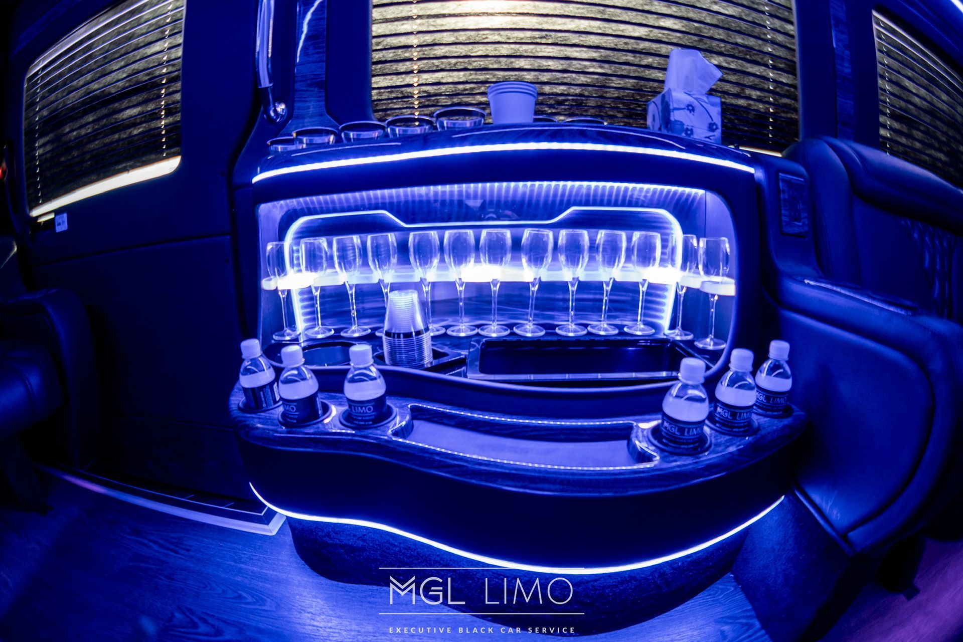 Bar inside a limousine with blue LED lighting and bottles.