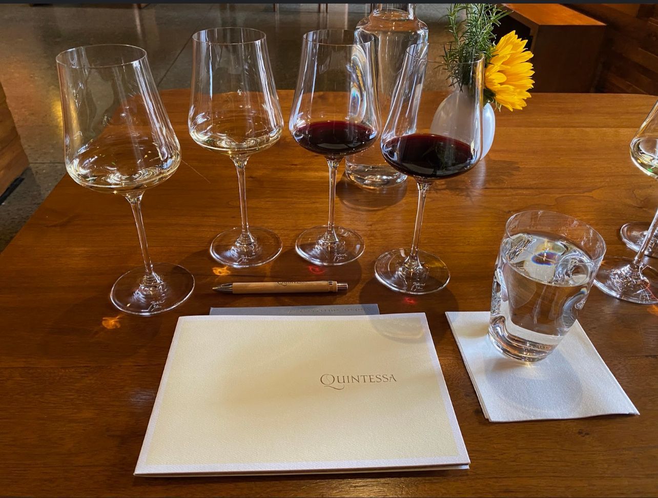 A wooden table topped with wine glasses and a menu