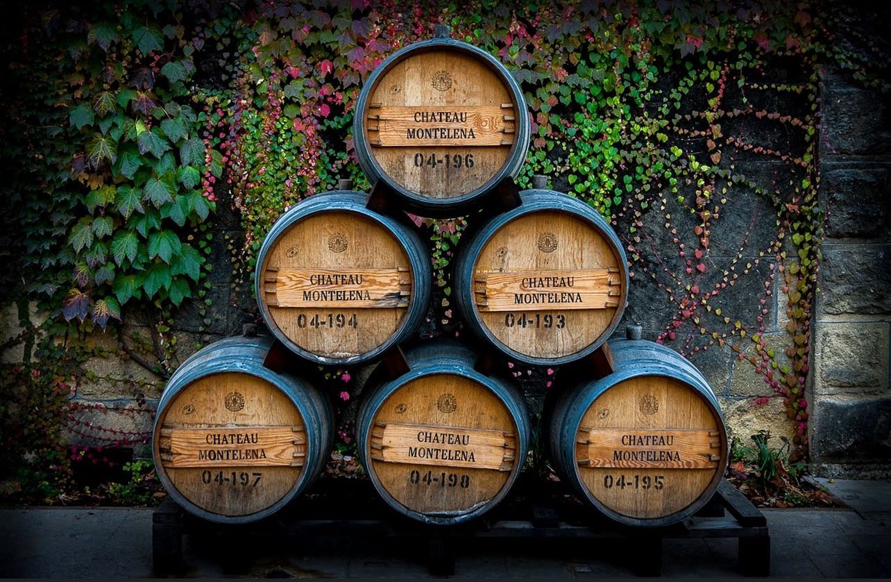 A stack of wooden barrels sitting in front of a stone wall.
