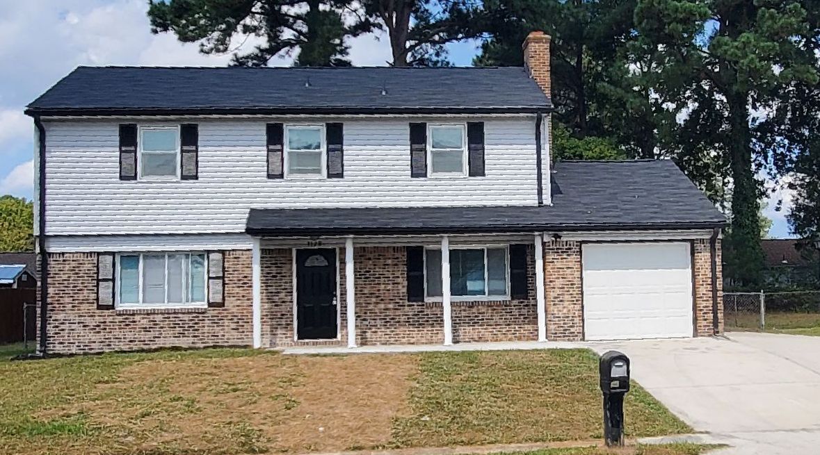 Two-story house with gray siding, brown brick facade, black shutters and a black roof. 