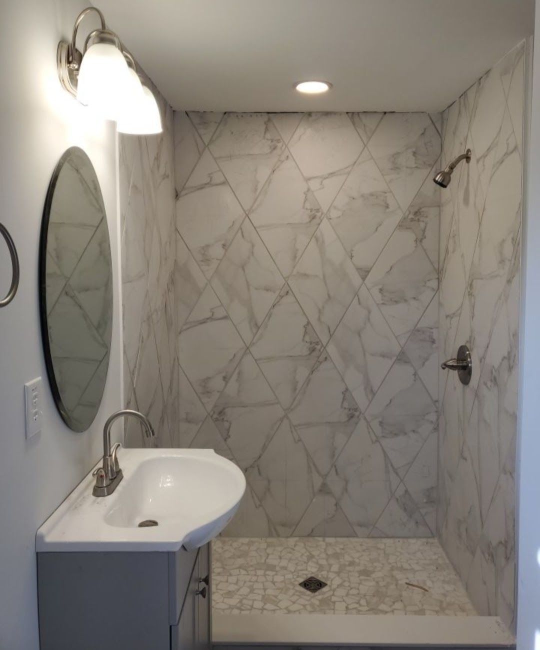 A small, modern bathroom with a walk-in shower and a sink. 