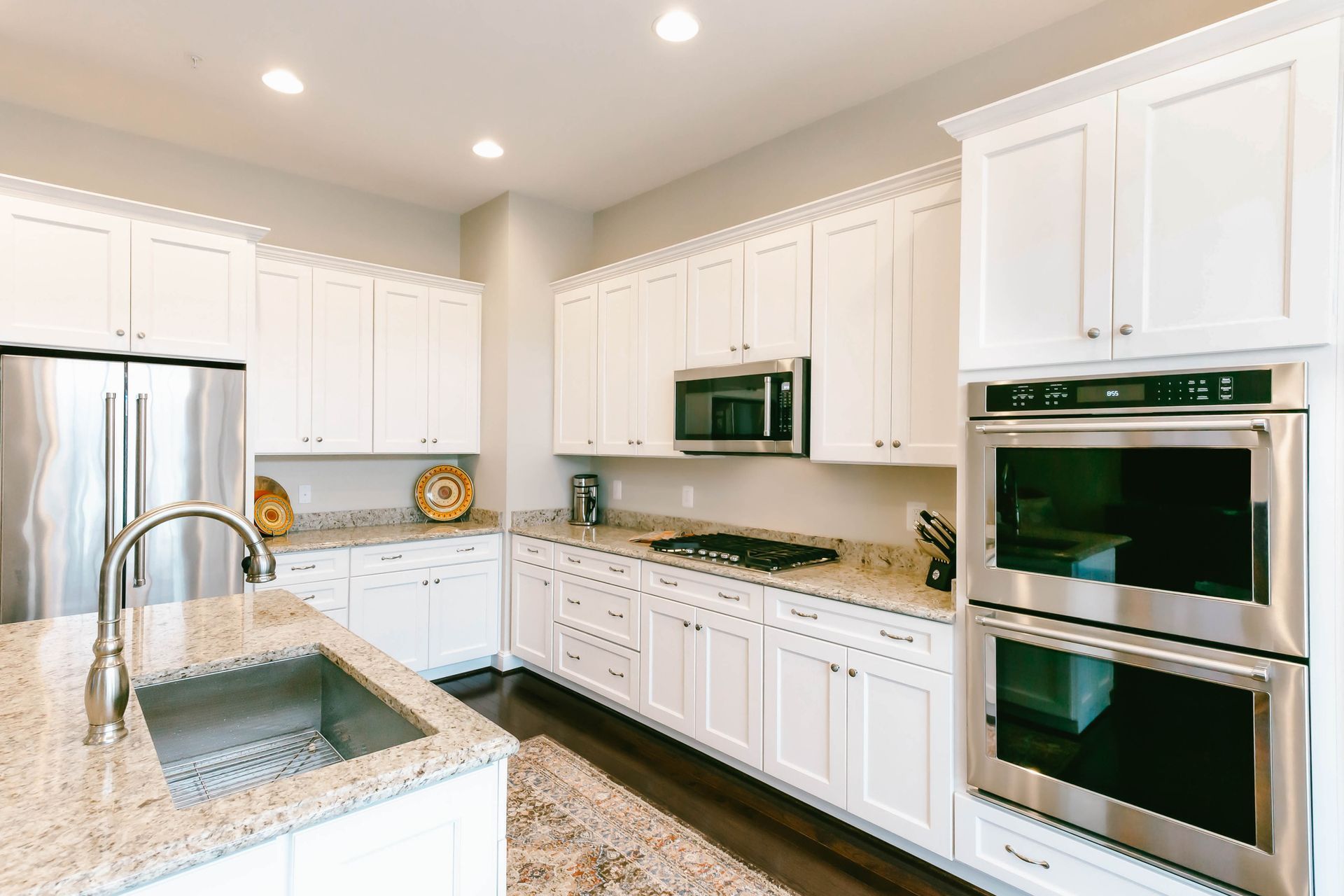 Modern kitchen with granite island, white cabinets, and stainless steel appliances.