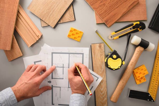 Hands-on designer at a desk writing on blueprints, developing an interior project.