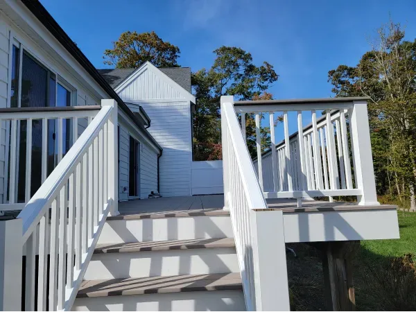 Two electricians working on an electrical panel outside a building. One holds a cable.