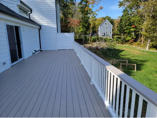 Trench dug in a grassy yard, leading to a house with black siding, and an electrical box.