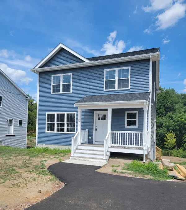 House under construction, with scaffolding and protective sheeting. Worker inside doorway.