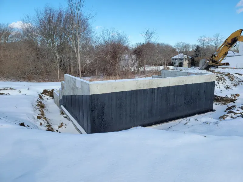 Two electricians working on an electrical panel outside a building. One holds a cable.