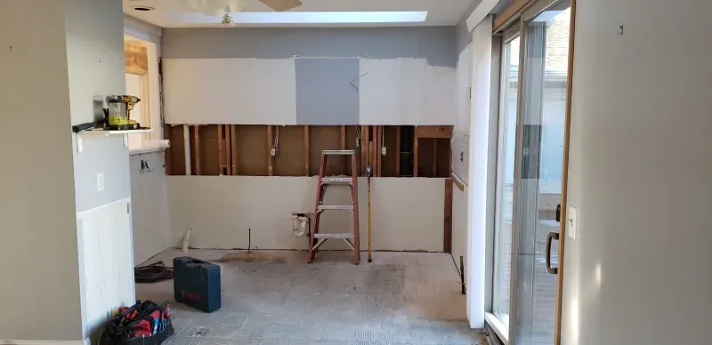 Trench dug in a grassy yard, leading to a house with black siding, and an electrical box.