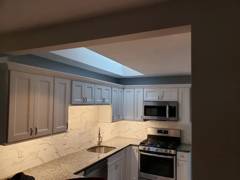 Kitchen with light gray cabinets, stainless steel appliances, and a skylight.