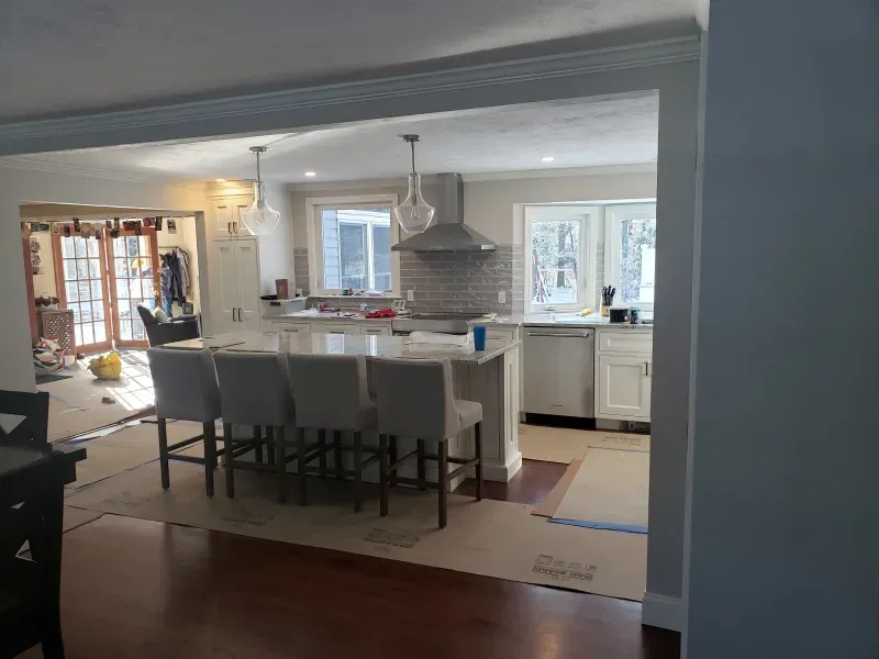 Trench dug in a grassy yard, leading to a house with black siding, and an electrical box.