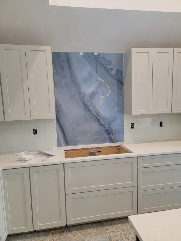 Kitchen remodel with light gray cabinets, white countertops, and blue marble backsplash.