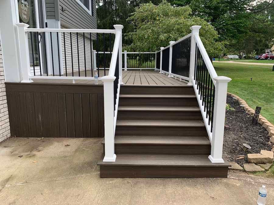 A deck with stairs leading up to it and a white railing.