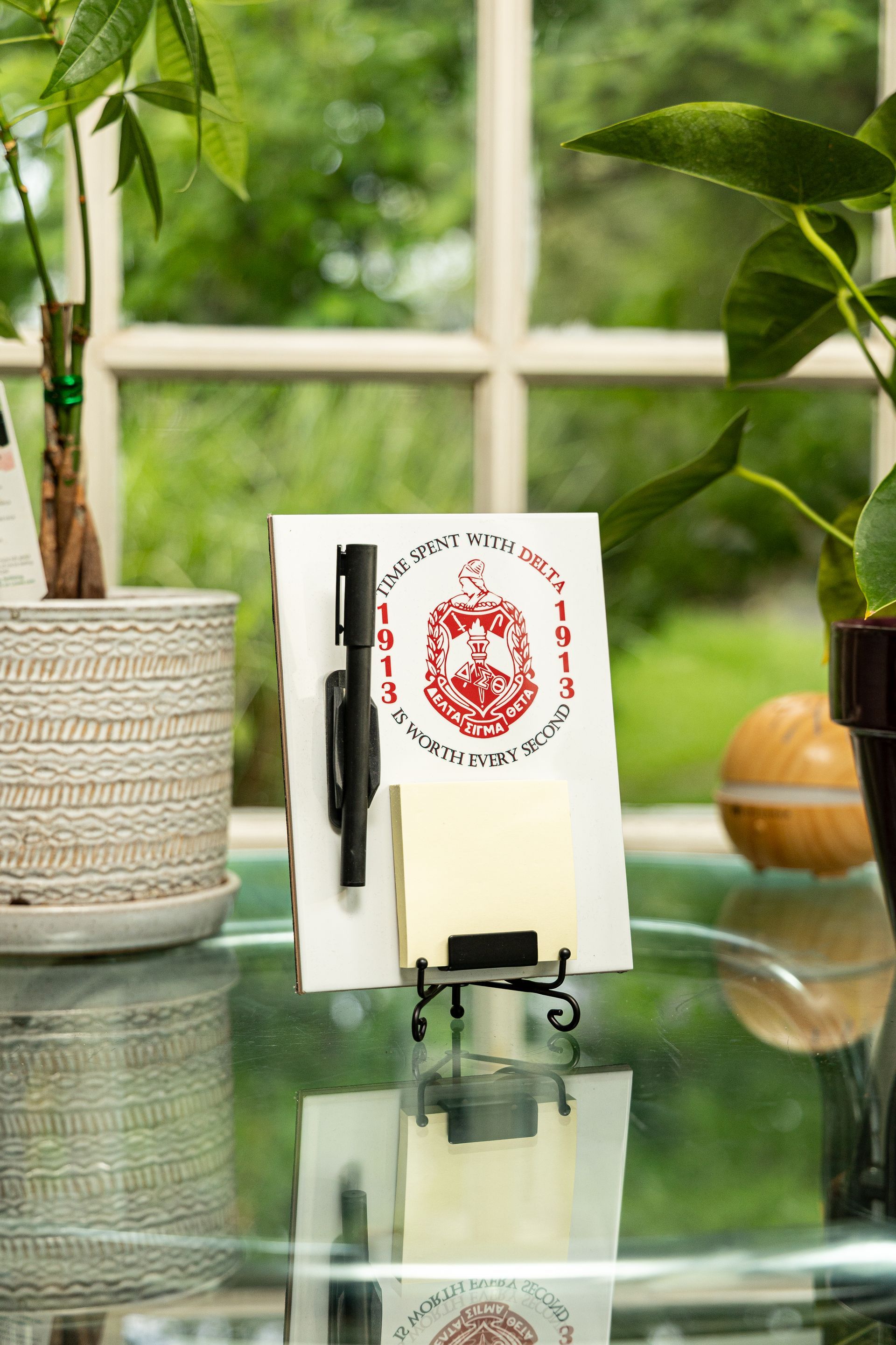 A notepad with a pen and sticky notes on a glass table.