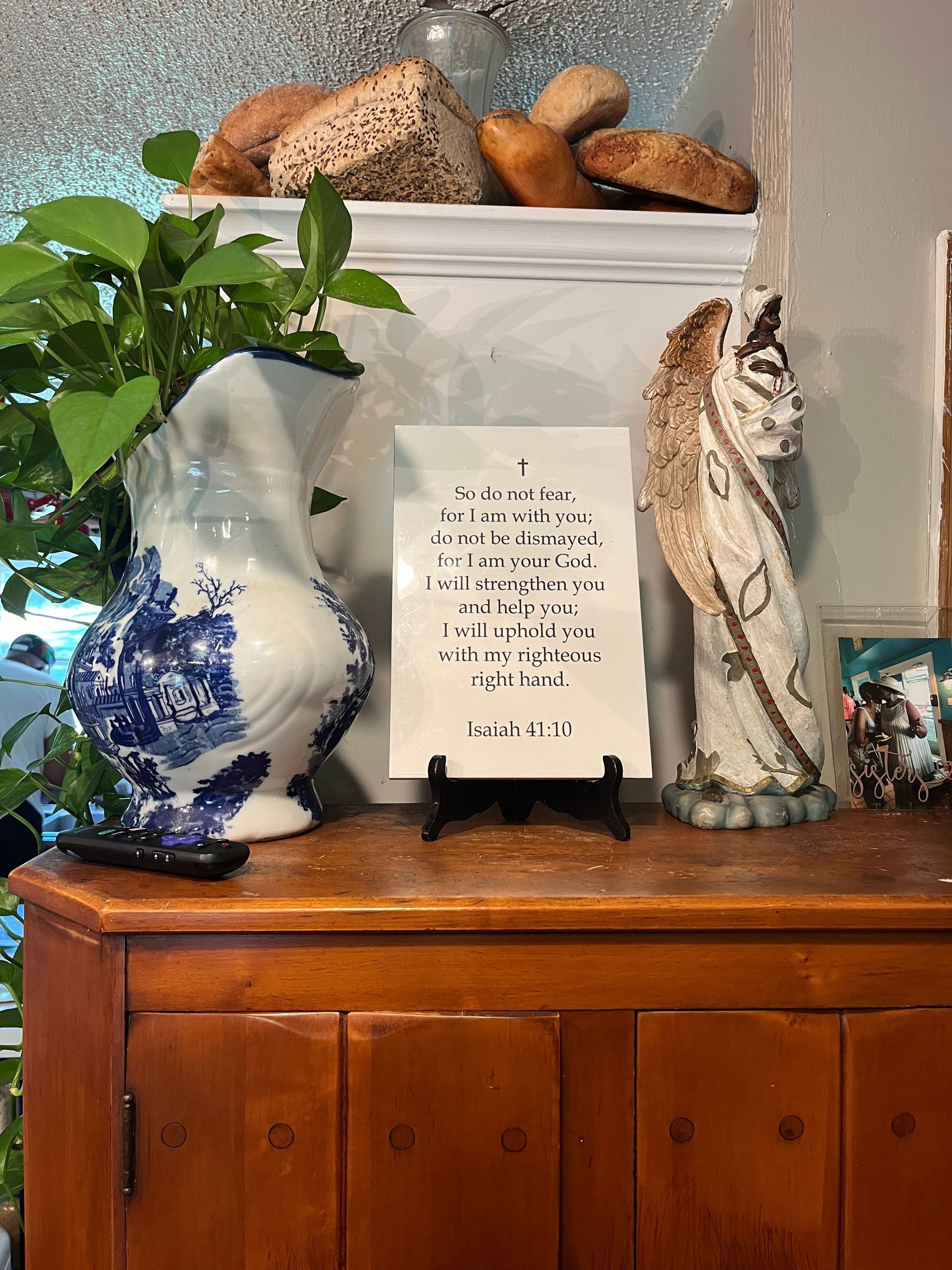 A blue and white vase is sitting on a wooden dresser next to a statue of an angel.