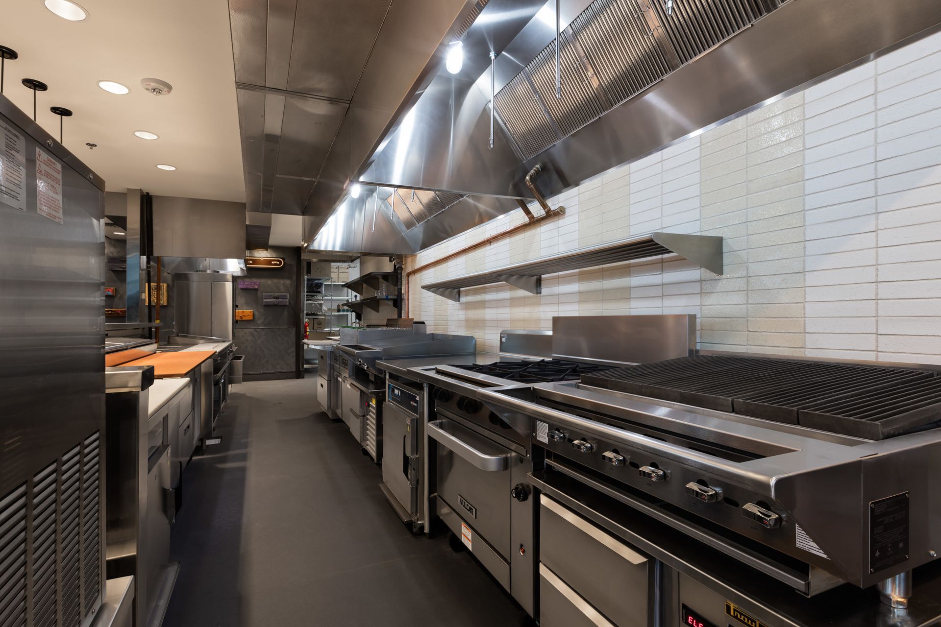 A long kitchen with a lot of stainless steel appliances.