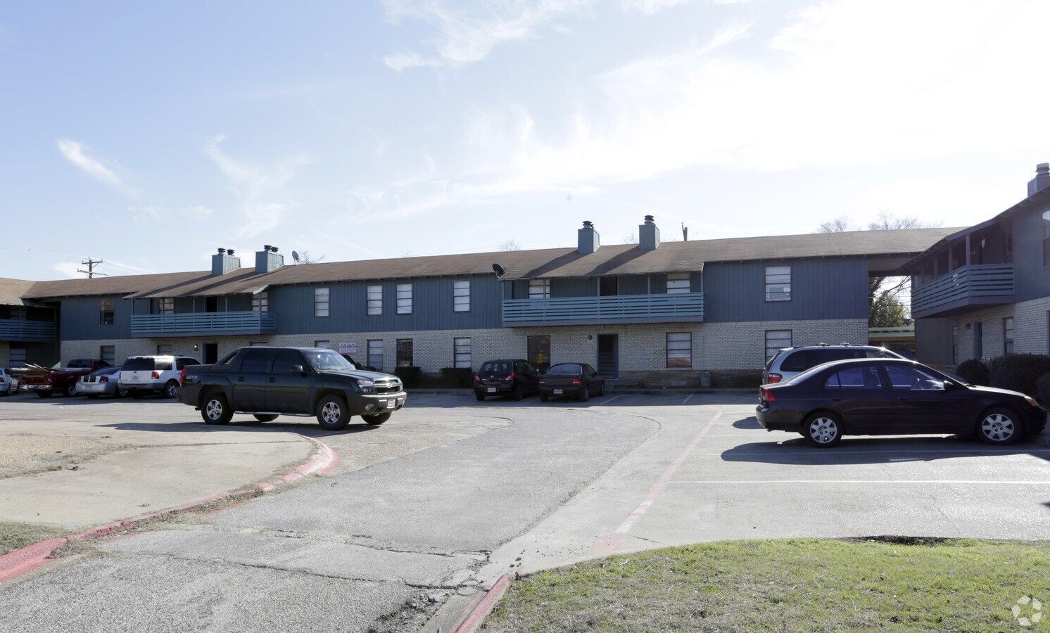 a row of apartment buildings with cars parked in front of them