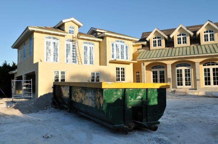 Residential construction site with a home dumpster rental for debris removal in the driveway. Residential construction site with a home dumpster rental for debris removal in the driveway.