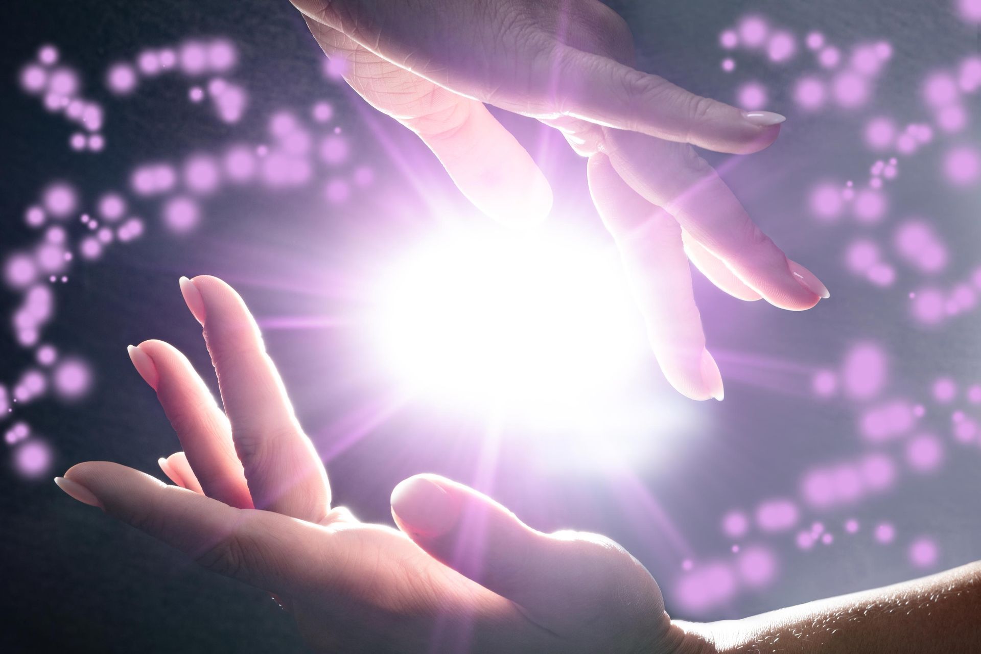 Hands reaching for a bright white light surrounded by sparkling purple dots.